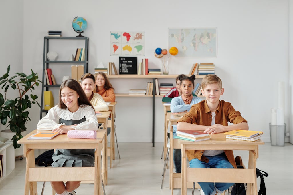A group of happy students sitting at desks in a modern classroom environment.