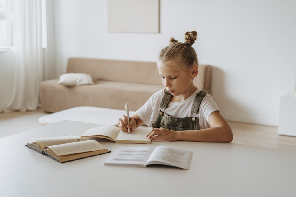 A young girl in a peaceful home setting focused on studying and writing in notebooks.