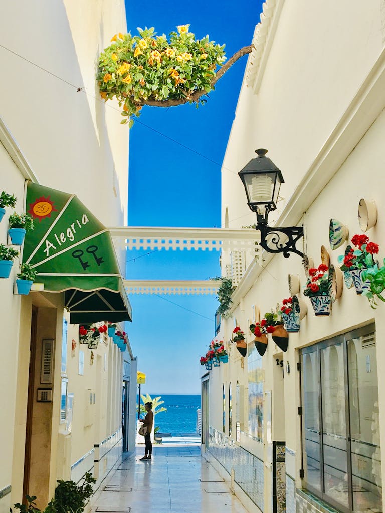 Bright alley in Torremolinos, Spain featuring vibrant flowers and Mediterranean decor.