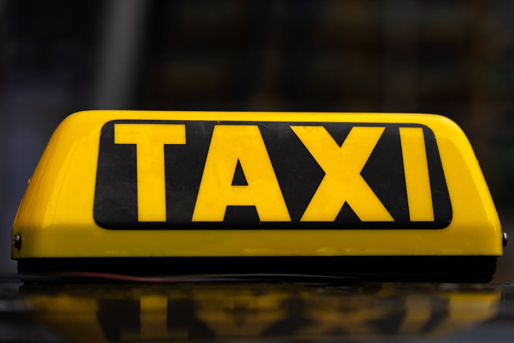 Bright yellow taxi sign on top of a vehicle, symbolizing public transportation.