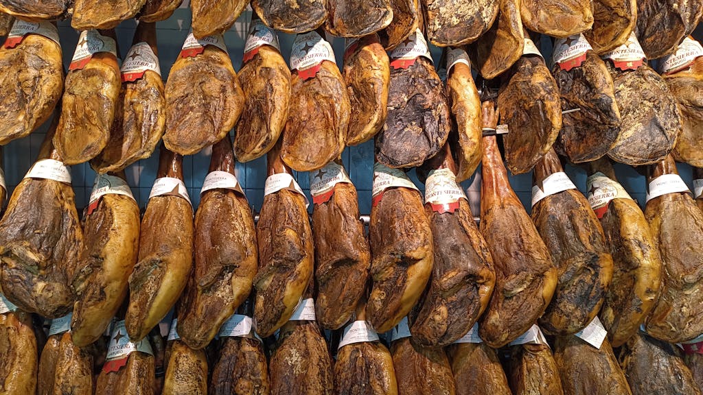 Captivating display of traditional Jamón Ibérico hanging in a vibrant Spanish market.
