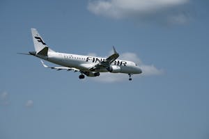 Finnair jet airliner in flight approaching Hamburg Airport on a clear day.