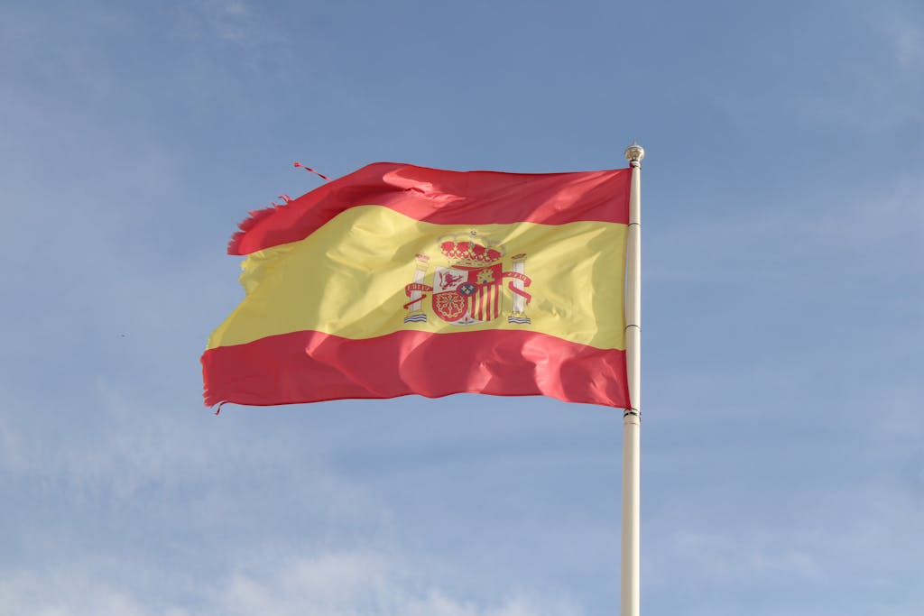 The Spanish flag flying against a clear sky in El Puerto de Santa María, Spain.