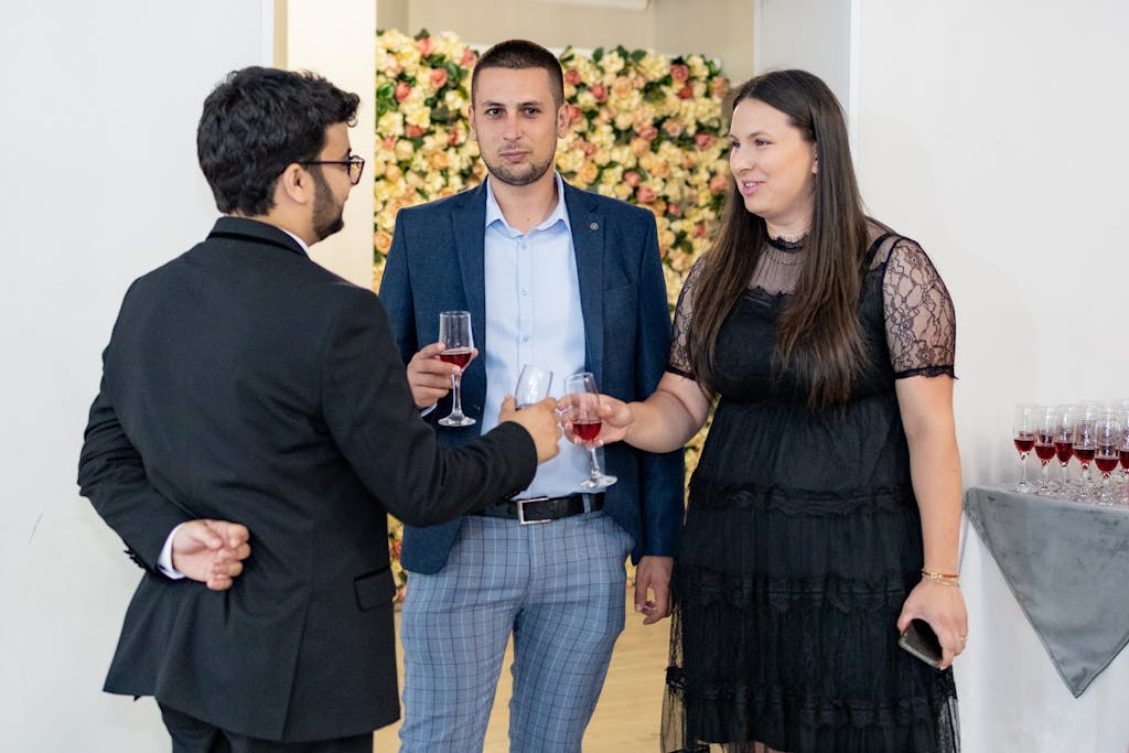Three adults sharing drinks and conversing at an indoor social event.