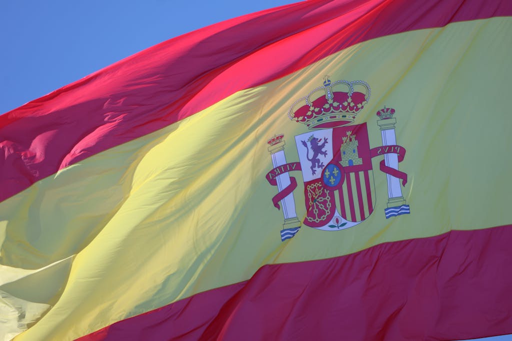 Vibrant Spanish flag waving against a clear blue sky in Cádiz, Andalucía.