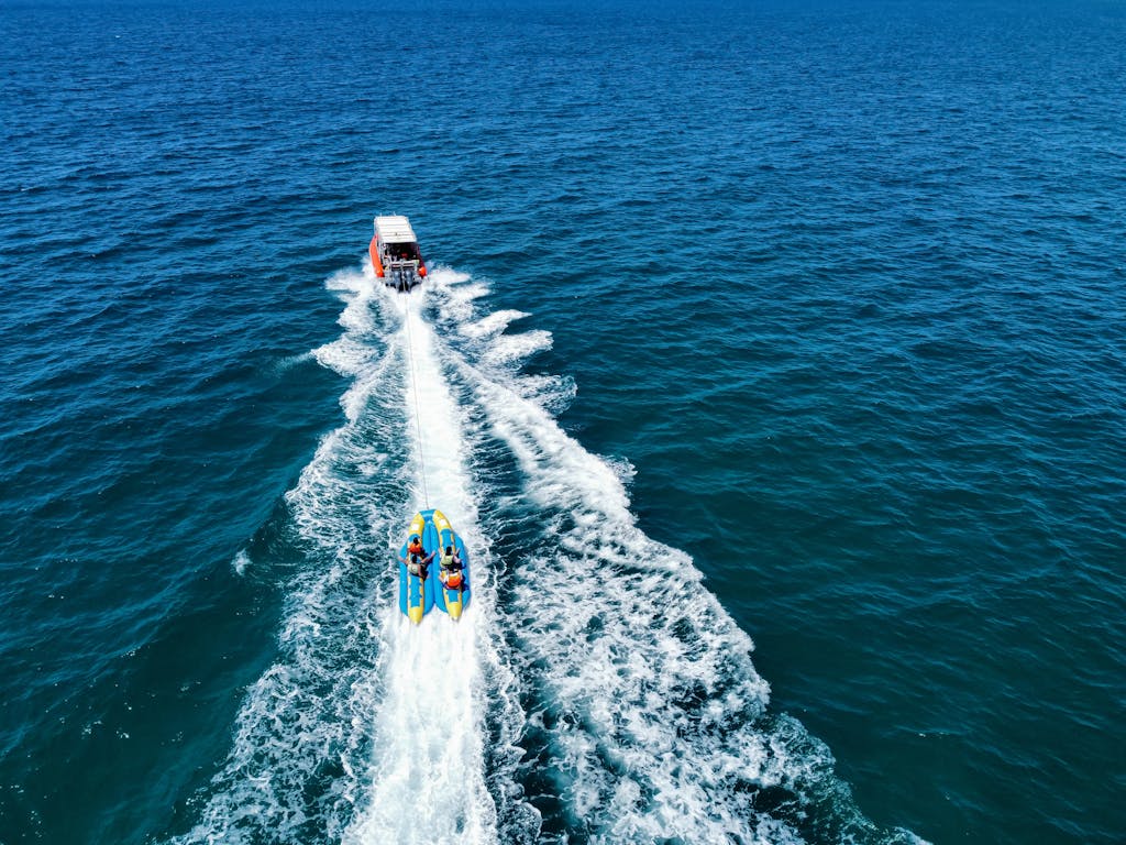 Exciting aerial view of a banana boat ride trailing a motorboat over the ocean.