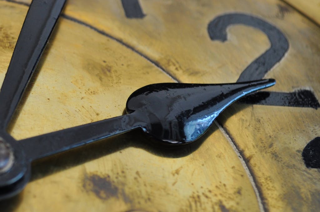 Macro shot of antique clock hands on a vintage clock face, emphasizing time.