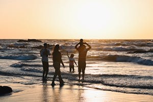 Perhe nauttii rannalla auringon laskiessa
