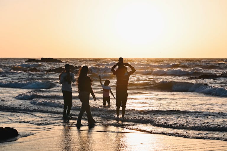 Perhe nauttii rannalla auringon laskiessa